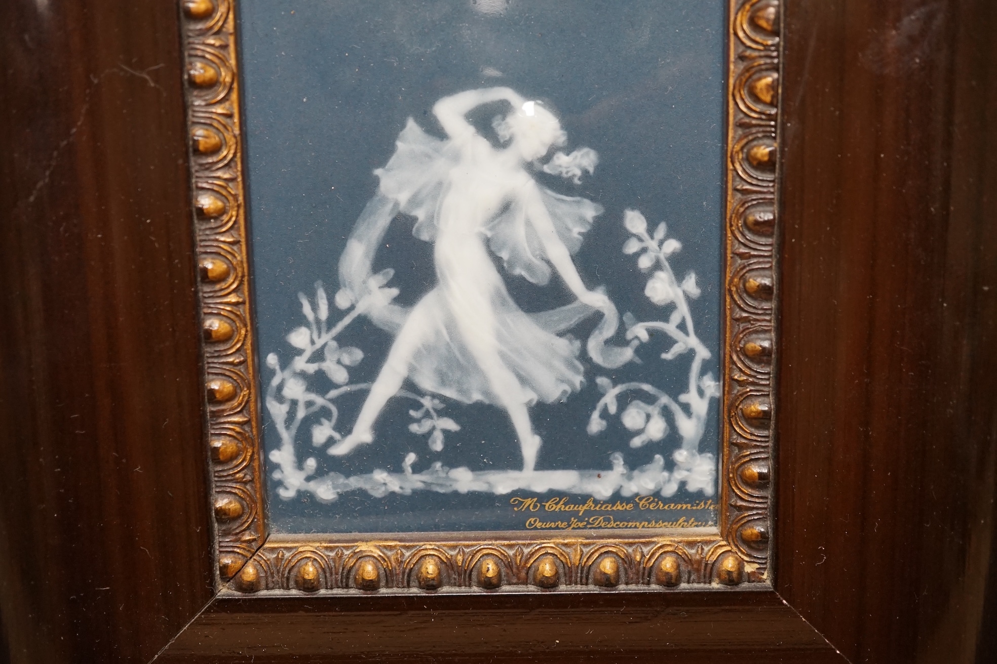 A framed Limoges blue and white pate-sur-pate plaque of a dancing fairy, signed Descomps, plaque 7cm x 10cm. Condition - good